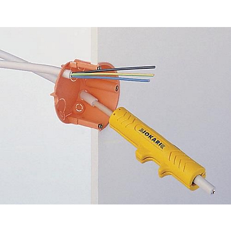 Un boîtier de jonction orange avec des fils et un outil JOKARI jaune. Les outils sont montés sur un mur.