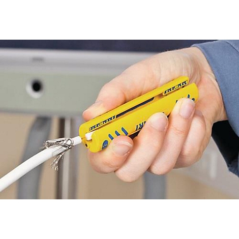 Une main tient un dénudeur de fil jaune. Un câble est en cours de dénudage.