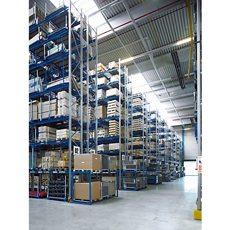 Groot magazijn met planken vol dozen en pallets. Helder plafond met dakramen.