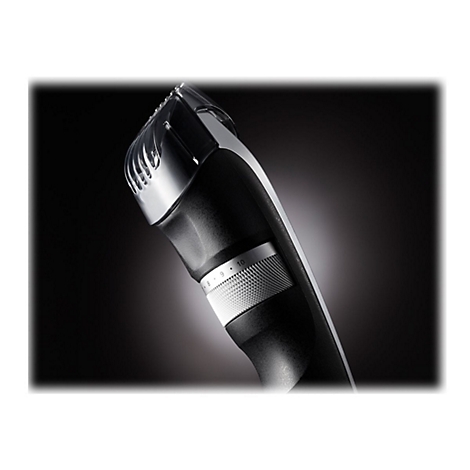 Gros plan sur une tondeuse à barbe noire. Des molettes de réglage et des lames sont visibles, placées sur un fond sombre.