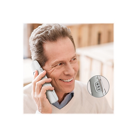 Ein lächelnder Mann telefoniert, hält ein weißes Telefon ans Ohr. Nahaufnahme zeigt das Telefon mit Lautstärketasten.