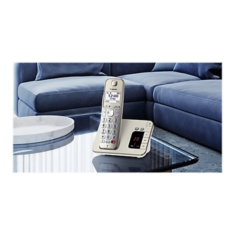 Ein elfenbeinfarbenes schnurloses Telefon mit Ladeschale steht auf einem Glastisch. Im Hintergrund ein blaues Sofa.