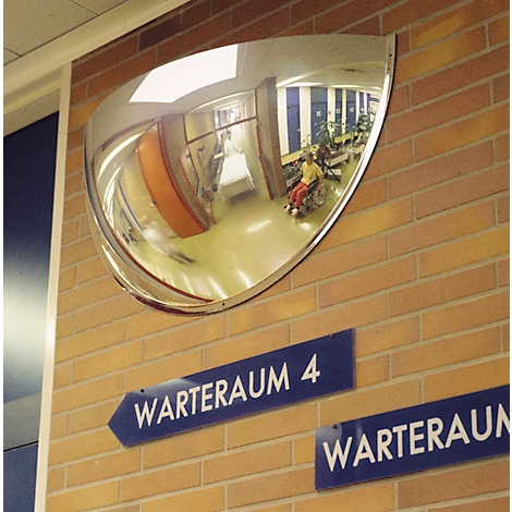 Ein halbkreisförmiger Spiegel an einer Backsteinwand über blauen Schildern mit der Aufschrift Warteraum.