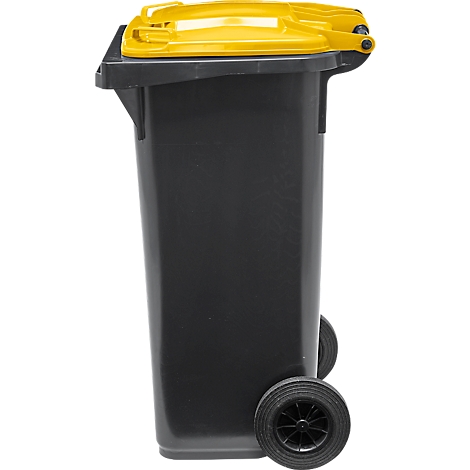 Contenedor de basura negro con tapa amarilla. Está sobre dos ruedas.