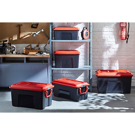 Schwarze und rote Aufbewahrungsboxen in einer Garage. Einige Boxen stehen, andere sind im Regal.