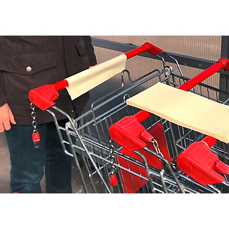 Gros plan sur les poignées de chariots de supermarché, avec des coussinets en papier jaune pour la désinfection. Une personne tient le chariot.