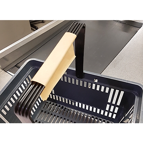 Un panier d'achat noir avec une poignée, posé sur un tapis roulant. La poignée est enveloppée de papier.