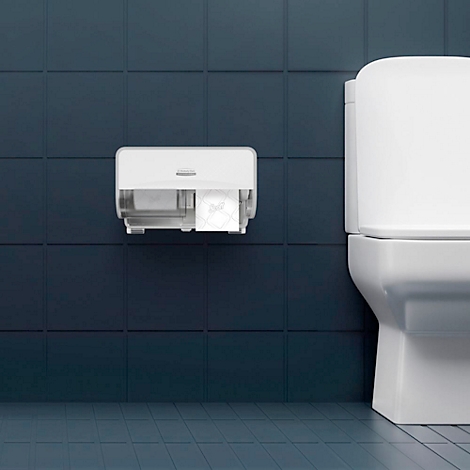 Distributeur de serviettes en papier blanc sur un mur bleu. À côté d'une cuvette de toilettes blanche. Un rouleau de papier est visible.