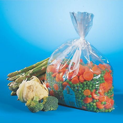 Un sac de légumes coupés, entouré d'asperges, de brocolis et de chou-fleur sur fond bleu.