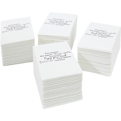 Quatre piles de serviettes carrées blanches. Chaque serviette porte la mention "Buen provecho...Enjoy your meal" en noir.