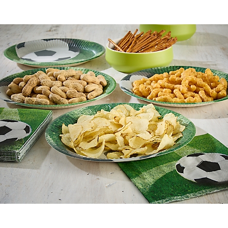 Verschillende snacks, zoals chips en pinda's, op borden met een voetbalontwerp. Op tafel liggen servetten met voetbalprints.