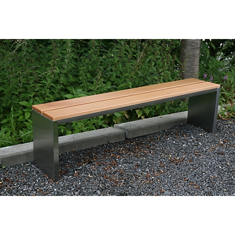 A wooden and metal park bench, on a gravel path, in front of dense greenery.