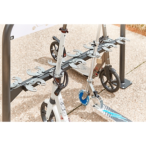 Two scooters in a scooter stand on a paved path. A white scooter stands in front, a gray one behind.