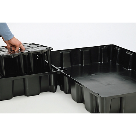 Eine Person platziert eine schwarze Kunststoffplatte auf einer anderen schwarzen Kunststoffplatte. Die Platten sind rechteckig und haben eine wabenartige Struktur.