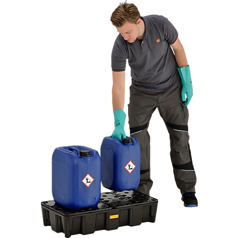 Man lifts a canister from a black spill pallet. Canisters are blue and labeled with hazardous materials symbols. The man is wearing gloves.