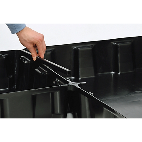 Person placing metal part into a black box. The arm is visible in the image.