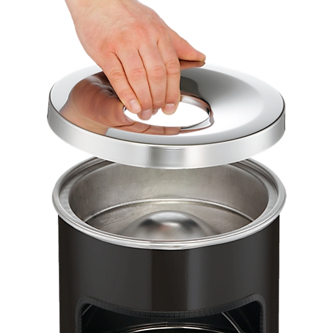 Hand lifting a shiny lid off a black trash can.