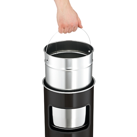 Hand holding a metal container with a handle, inserted into a black cylinder. There is also a metal container inside the cylinder.