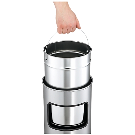 Hand lifting a metallic inner bucket from a trash can. The bucket has a carrying handle.
