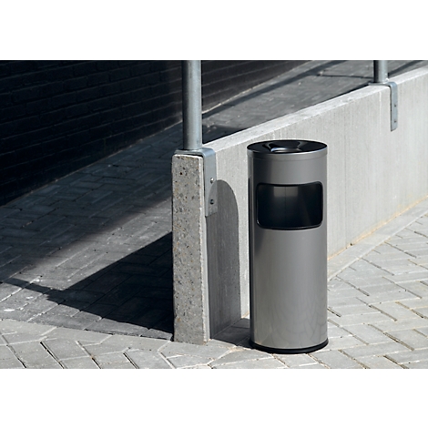 Gray trash can on a paved walkway next to a concrete pillar.