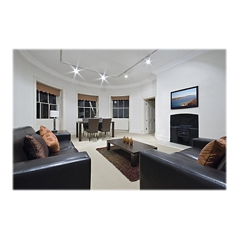 Wohnzimmer mit schwarzem Ledersofa, Fernseher, Kamin und Fenster. Ein Tisch mit Stühlen und Kaffeetisch ist auch zu sehen.