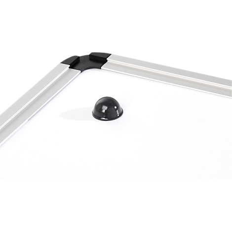 Detail van een wit whiteboard met zilveren frame, zwart hoekstuk en magnetische knop.
