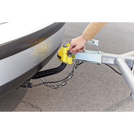A person attaching a trailer coupling to a car. The yellow part of the coupling is being locked securely.
