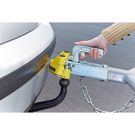 Close-up of a car with a trailer hitch. A hand is operating the trailer hitch system.