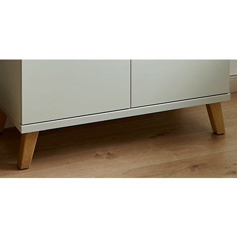 Gros plan d'un meuble gris clair avec des pieds en bois, posé sur un plancher en bois.