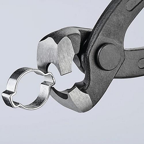 Gros plan d'une pince tenant un anneau de collier de serrage argenté.