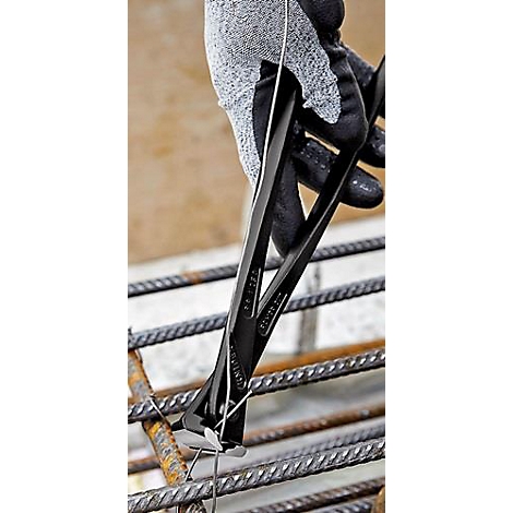 Gros plan : personne en gants tenant une pince sur un treillis métallique. Gants noirs et gris, pince sombre, barres d'acier.
