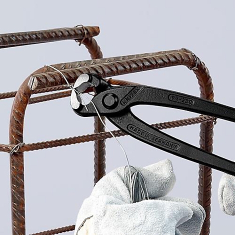 Pince à fil noire pliage de fil sur renfort. Un gant blanc tient le fil. La pince porte la mention "KNIPEX".