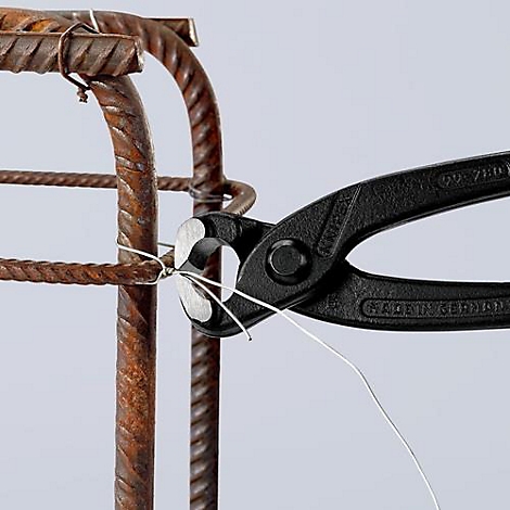 Une pince noire attache du fil de fer autour d'acier d'armature, avec une armature en acier en arrière-plan.