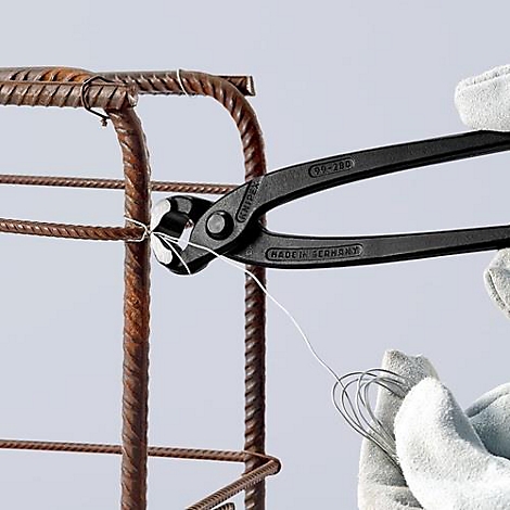 Pince noire liant du fil autour d'une armature en acier. Gants tenant la pince. Le fond est clair.