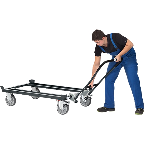 A man in blue work clothes operates a transport trolley. The trolley is loaded.