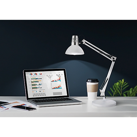 Desk with laptop, lamp and coffee cup. Charts are visible on the screen.