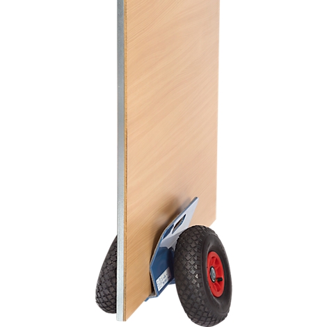 A wooden board on a hand truck. The wheels are black and red, the board is light brown.
