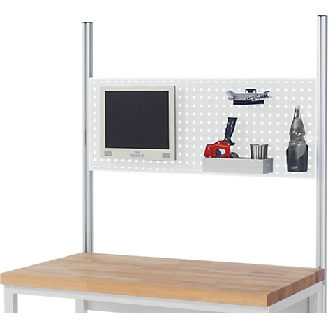 Établi avec panneau perforé, moniteur, outils et bouteille.
