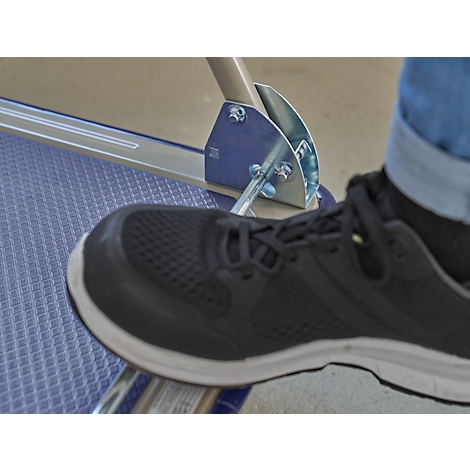 A black sneaker stands on a blue patterned footboard connected to silver metal parts.