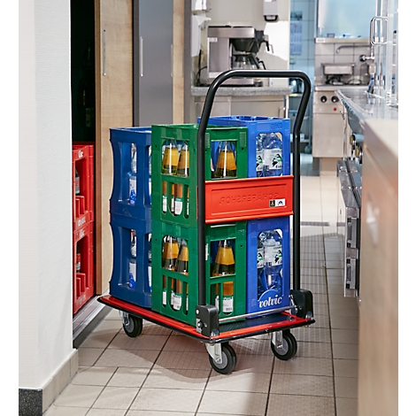 Een drankentrolley met kratten vol drank in een keuken. Blauwe, groene en rode kratten met mineraalwater en sap. De trolley heeft vier wielen.