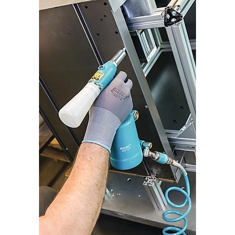 Persoon houdt blauwe pneumatische gereedschappen vast. De hand draagt een grijze handschoen, de gereedschapsbehuizing is lichtblauw met een witte handgreep. Op de achtergrond een metalen frame.