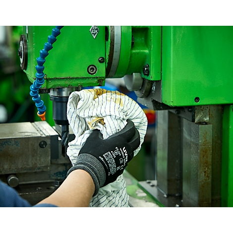 Een persoon veegt een werktuigmachine af met een doek. Ze dragen een zwarte handschoen.