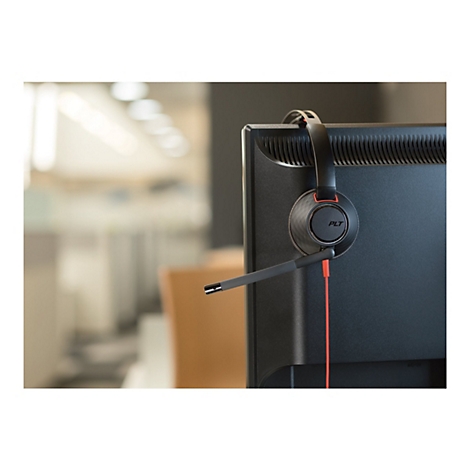 Ein schwarzes Plantronics-Headset mit rotem Kabel hängt über der Oberkante eines schwarzen Computermonitors.