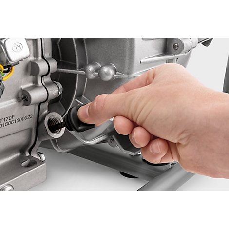 Gros plan d'une main insérant un bouchon noir dans un trou sur un boîtier métallique.