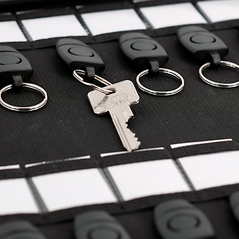 Gros plan sur un porte-clés avec des clés. Tissu noir avec des carrés blancs. Une clé se démarque.