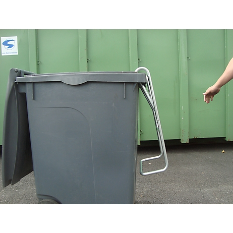 Poubelle grise avec couvercle ouvert et poignée métallique. Une main tend la main.