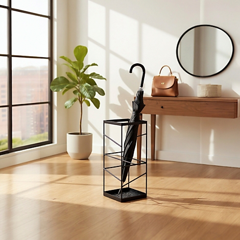 Parapluie noir dans un support métallique. Plancher en bois, fenêtre, plante en pot et miroir rond.