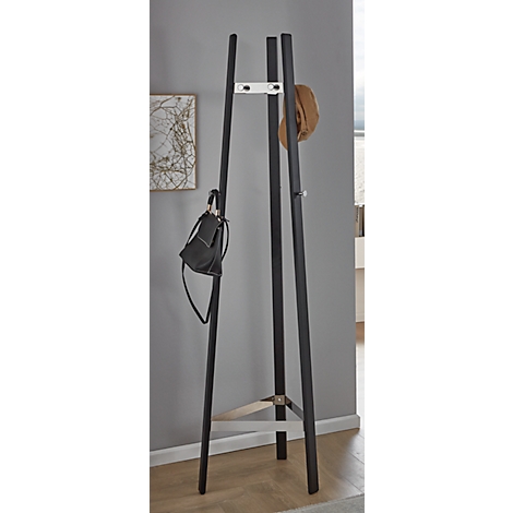 Porte-manteau noir avec chapeau et sac à main. Sur parquet clair contre un mur gris.