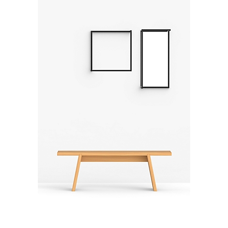 Banc en bois devant un mur blanc avec des cadres noirs.