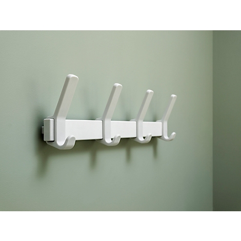 Patère murale blanche avec quatre crochets contre un mur vert clair.